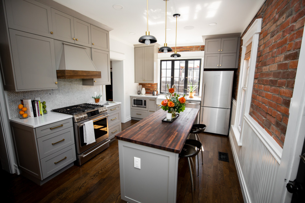 Inspiration for a small transitional l-shaped separate kitchen in Denver with a farmhouse sink, shaker cabinets, grey cabinets, quartz benchtops, white splashback, marble splashback, stainless steel appliances, dark hardwood floors, with island, brown floor and white benchtop.
