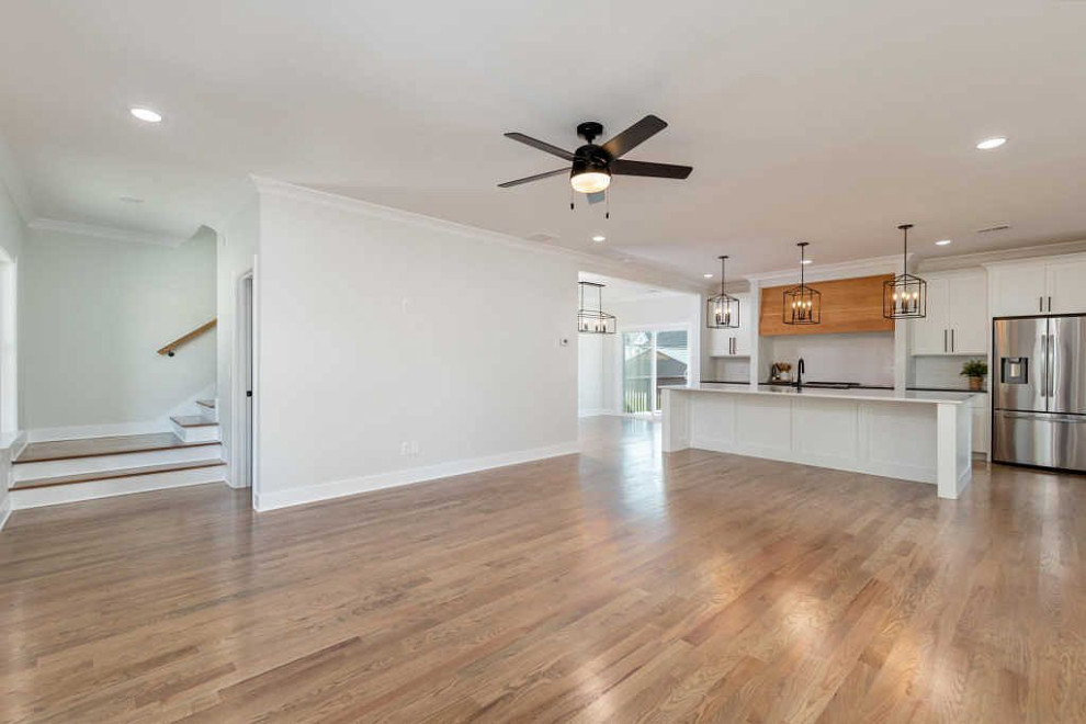 Open concept kitchen - large transitional galley medium tone wood floor and brown floor open concept kitchen idea with an undermount sink, shaker cabinets, white cabinets, quartz countertops, white backsplash, ceramic backsplash, stainless steel appliances, an island and white countertops
