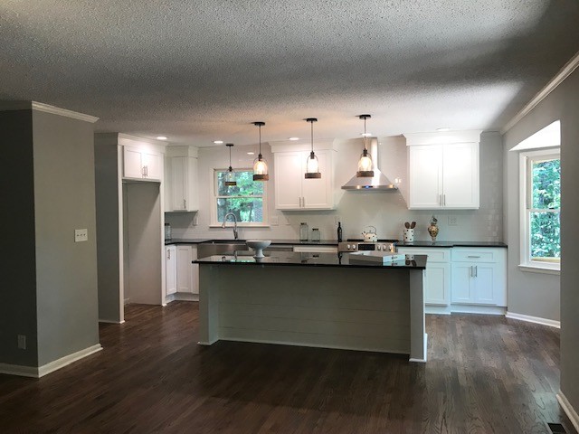 Eat-in kitchen - mid-sized transitional l-shaped medium tone wood floor and brown floor eat-in kitchen idea with a farmhouse sink, shaker cabinets, white cabinets, granite countertops, white backsplash, subway tile backsplash, stainless steel appliances, an island and black countertops