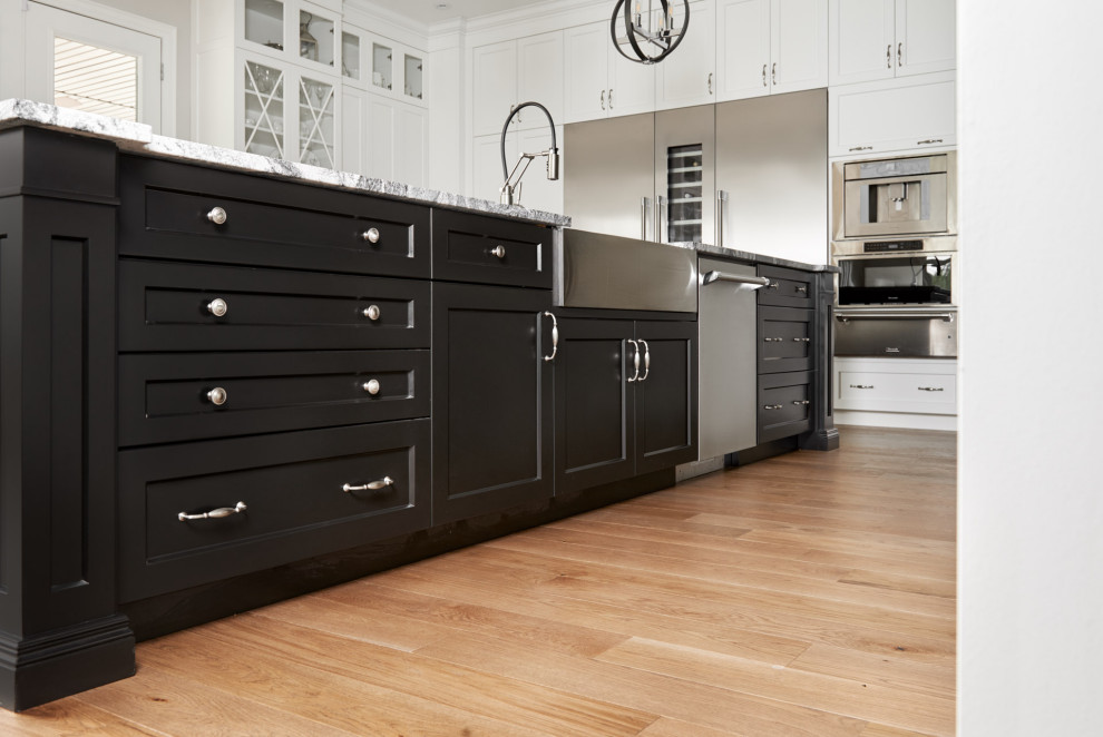 Inspiration for a huge transitional light wood floor and brown floor eat-in kitchen remodel in Toronto with a farmhouse sink, shaker cabinets, white cabinets, granite countertops, gray backsplash, granite backsplash, stainless steel appliances, an island and gray countertops