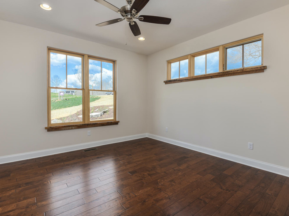 Photo of a large country guest bedroom in Other with beige walls, medium hardwood floors, no fireplace and brown floor.