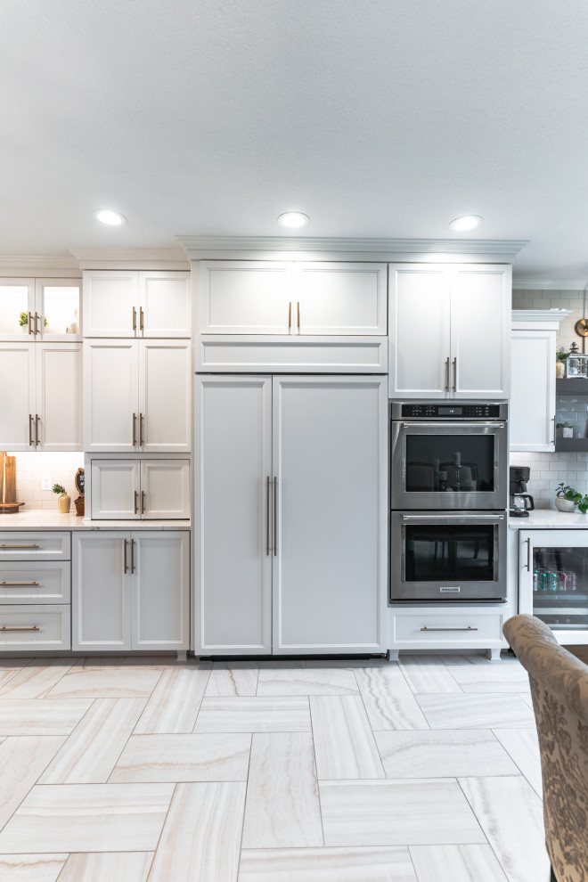 Exempel på ett mycket stort klassiskt vit linjärt vitt kök med öppen planlösning, med en undermonterad diskho, släta luckor, vita skåp, bänkskiva i kvarts, vitt stänkskydd, stänkskydd i keramik, rostfria vitvaror, klinkergolv i keramik, en köksö och flerfärgat golv