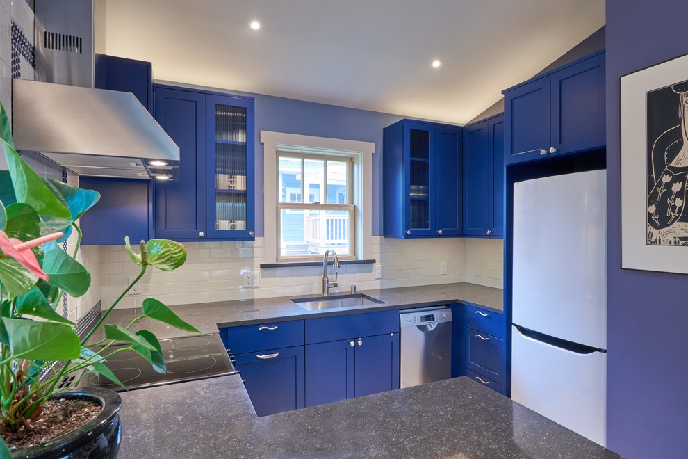 Inspiration for a small transitional kitchen in Seattle with an undermount sink, flat-panel cabinets, blue cabinets, quartz benchtops, white splashback, subway tile splashback, stainless steel appliances, porcelain floors and blue benchtop.