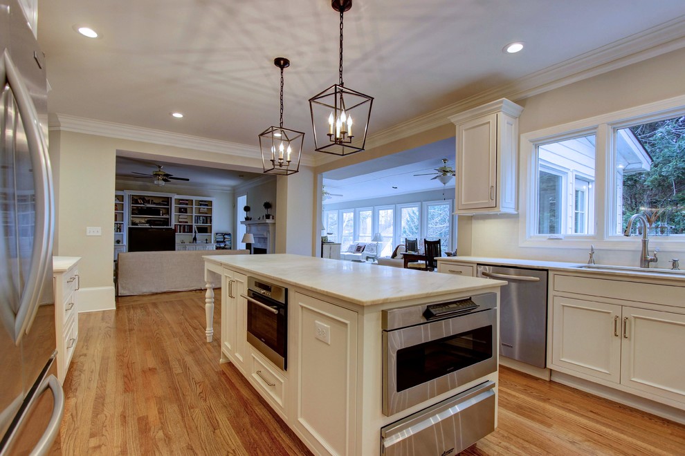Large transitional u-shaped light wood floor kitchen pantry photo in Atlanta with an undermount sink, recessed-panel cabinets, white cabinets, quartz countertops, white backsplash, subway tile backsplash, stainless steel appliances and an island