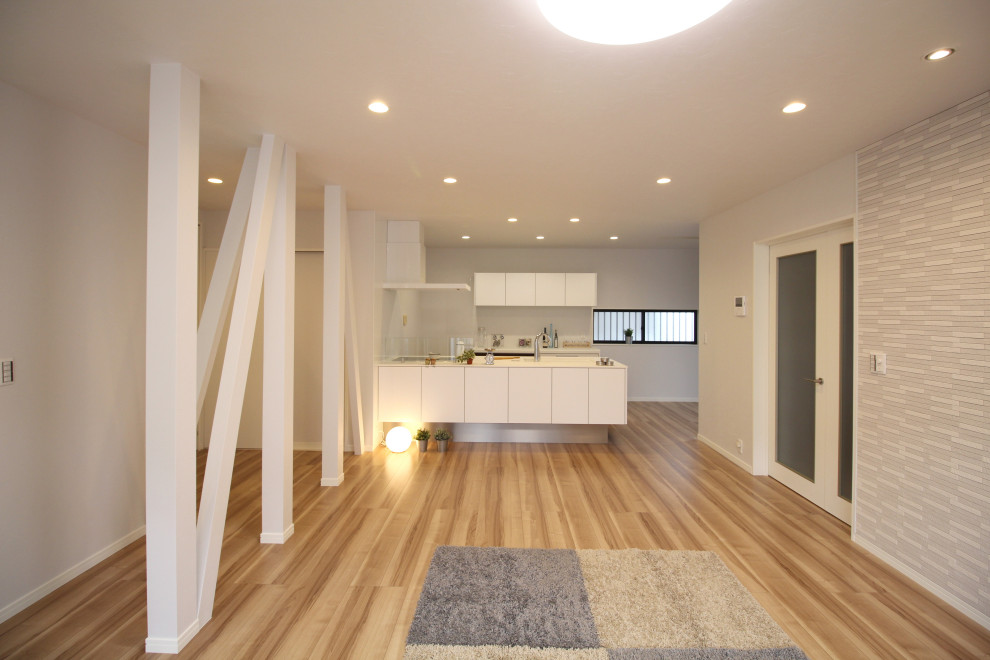This is an example of a medium sized modern single-wall open plan kitchen in Other with an integrated sink, flat-panel cabinets, white cabinets, composite countertops, white splashback, painted wood flooring, an island, beige floors, white worktops and a wallpapered ceiling.
