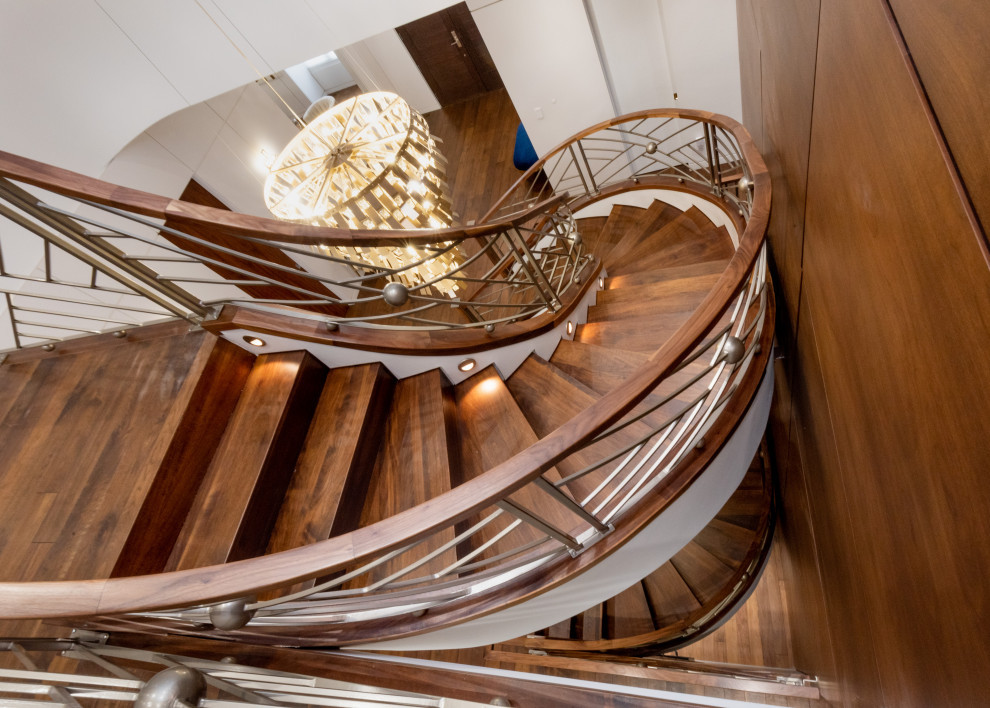 Expansive classic wood spiral mixed railing staircase in Toronto with wood risers and wood walls.