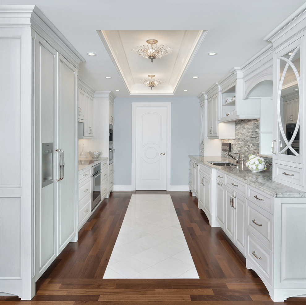 Inspiration for a traditional galley kitchen in Miami with an undermount sink, raised-panel cabinets, white cabinets, multi-coloured splashback, panelled appliances and dark hardwood floors.