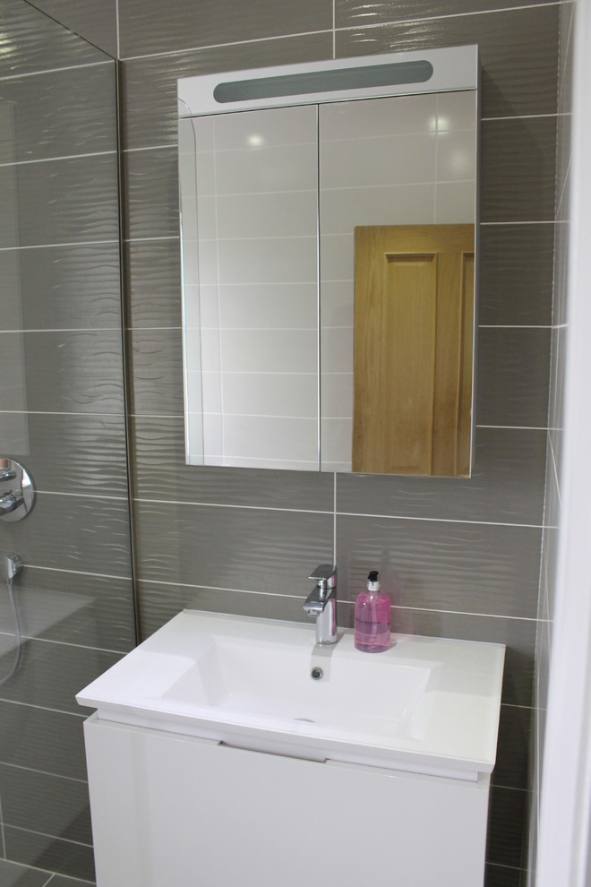 Photo of a small contemporary bathroom in Essex with a wall-mount sink, a wall-mount toilet, gray tile and porcelain tile.