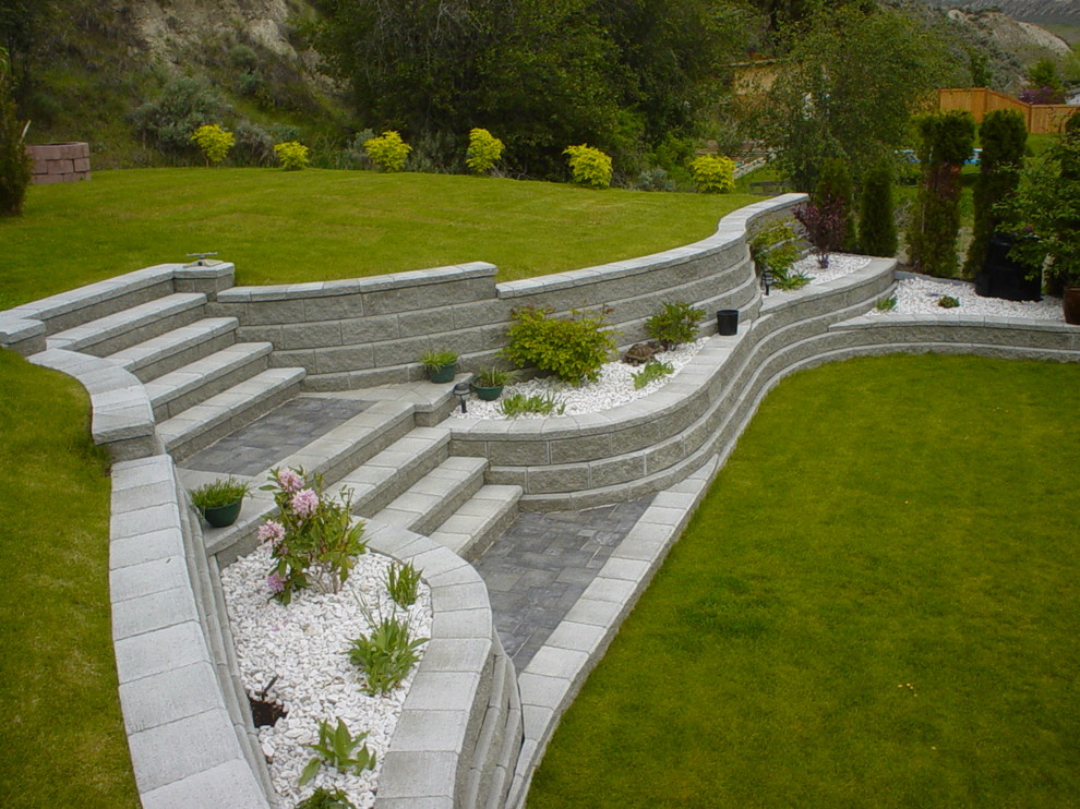 Large country sloped full sun garden in Vancouver with a retaining wall.