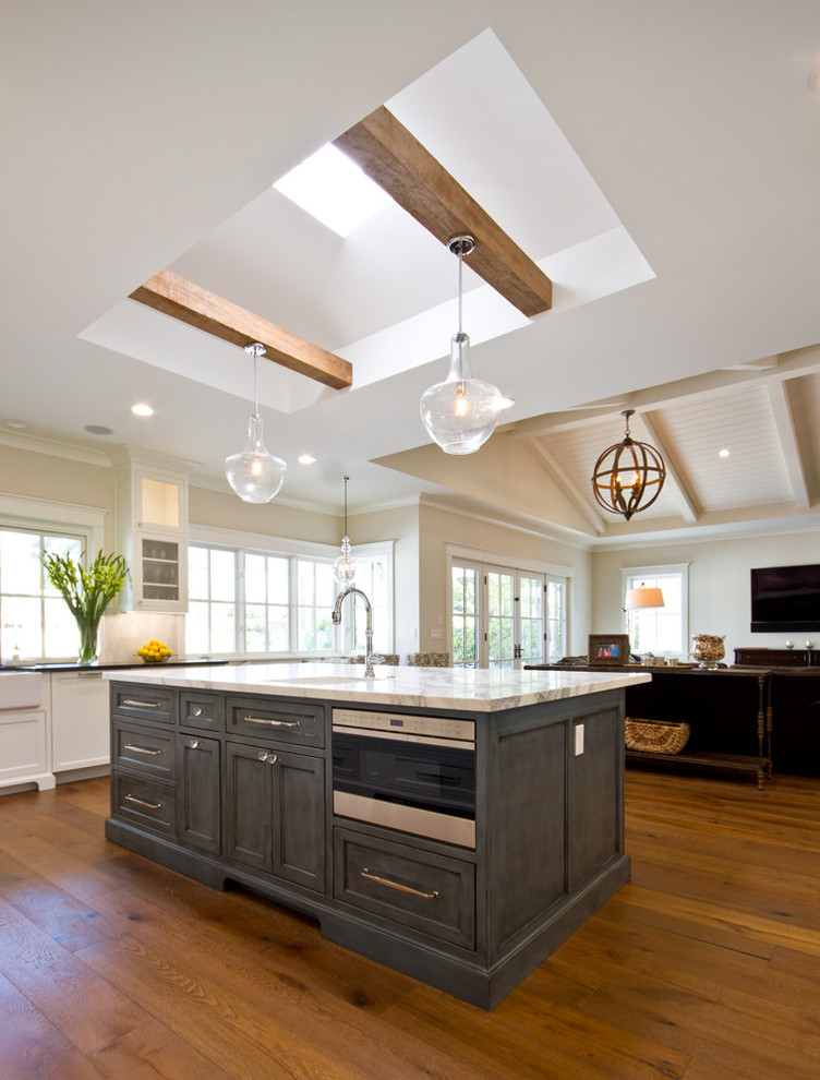 Eat-in kitchen - large transitional u-shaped medium tone wood floor eat-in kitchen idea in Phoenix with a farmhouse sink, recessed-panel cabinets, white cabinets, marble countertops, white backsplash, stone tile backsplash, stainless steel appliances and an island