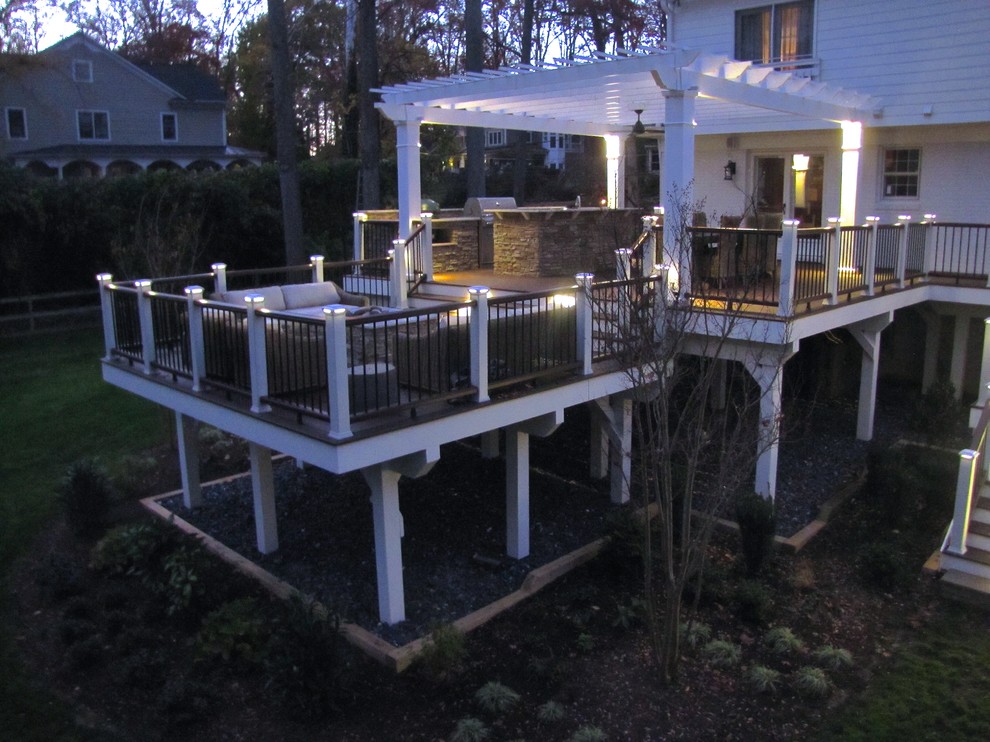 This is an example of a large traditional backyard deck in DC Metro with an outdoor kitchen and a pergola.