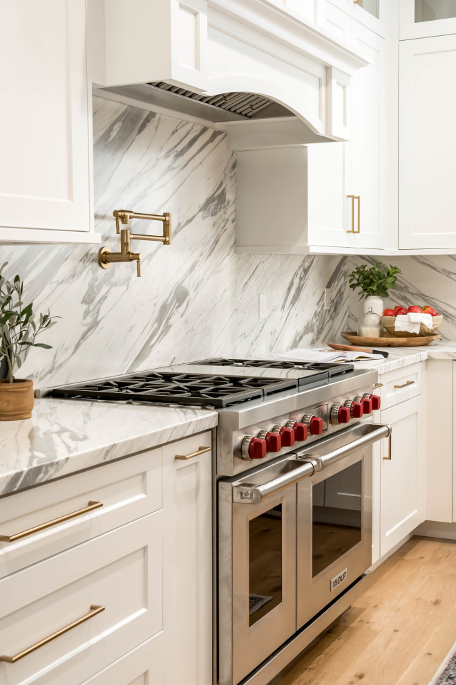 Exempel på ett stort klassiskt flerfärgad flerfärgat kök, med en rustik diskho, luckor med infälld panel, vita skåp, marmorbänkskiva, flerfärgad stänkskydd, stänkskydd i marmor, integrerade vitvaror, ljust trägolv, en köksö och brunt golv