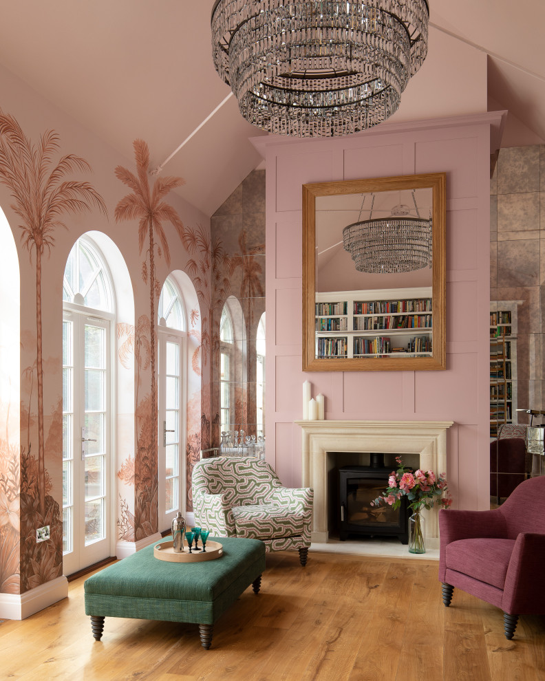 This is an example of a large classic open plan living room feature wall in Sussex with a music area, pink walls, light hardwood flooring, a wood burning stove, a stone fireplace surround, beige floors and a vaulted ceiling.