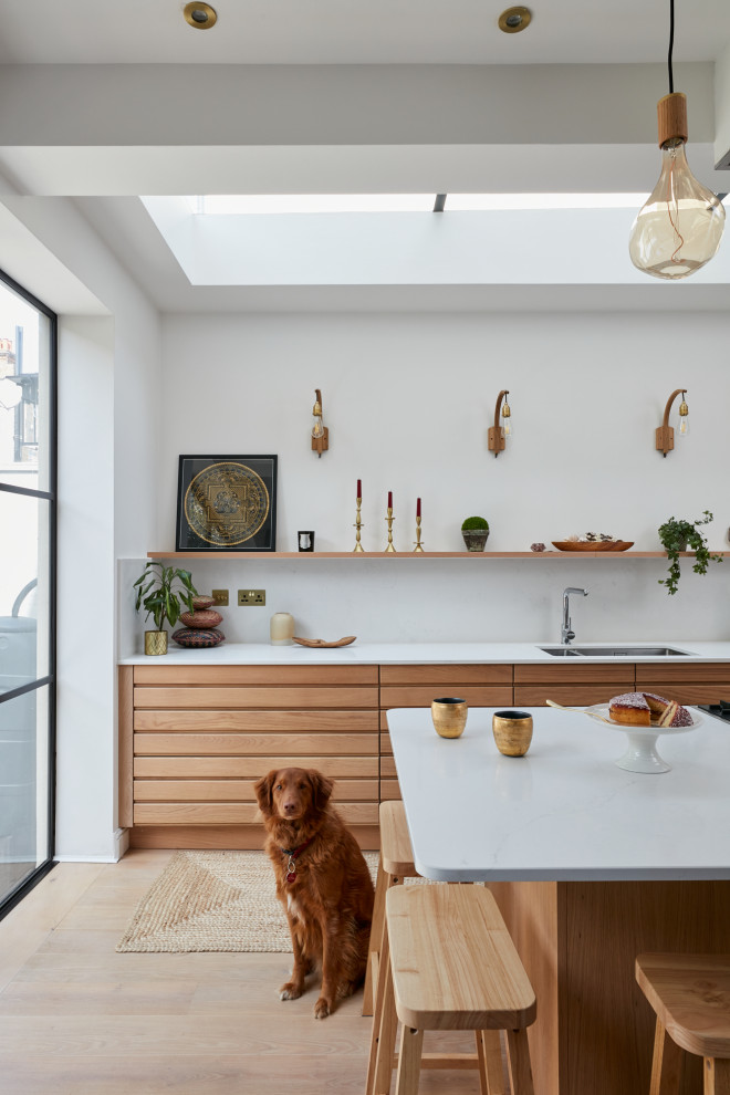 Mid-sized scandinavian open plan kitchen in London with solid surface benchtops and with island.