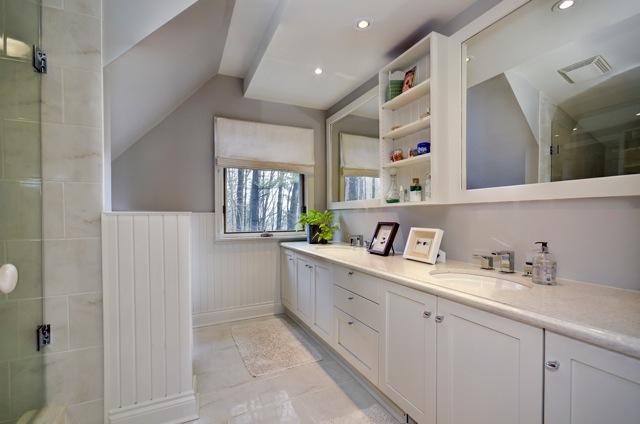 This is an example of a transitional bathroom in Toronto with an undermount sink, a freestanding tub, a two-piece toilet, shaker cabinets, white cabinets, engineered quartz benchtops and white tile.