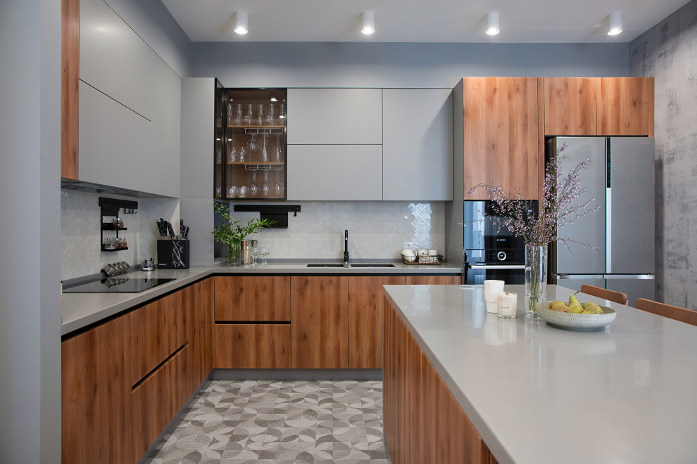 Photo of a large contemporary l-shaped separate kitchen in Yekaterinburg with a double-bowl sink, flat-panel cabinets, grey cabinets, solid surface benchtops, white splashback, mosaic tile splashback, black appliances, porcelain floors, with island, grey floor and grey benchtop.