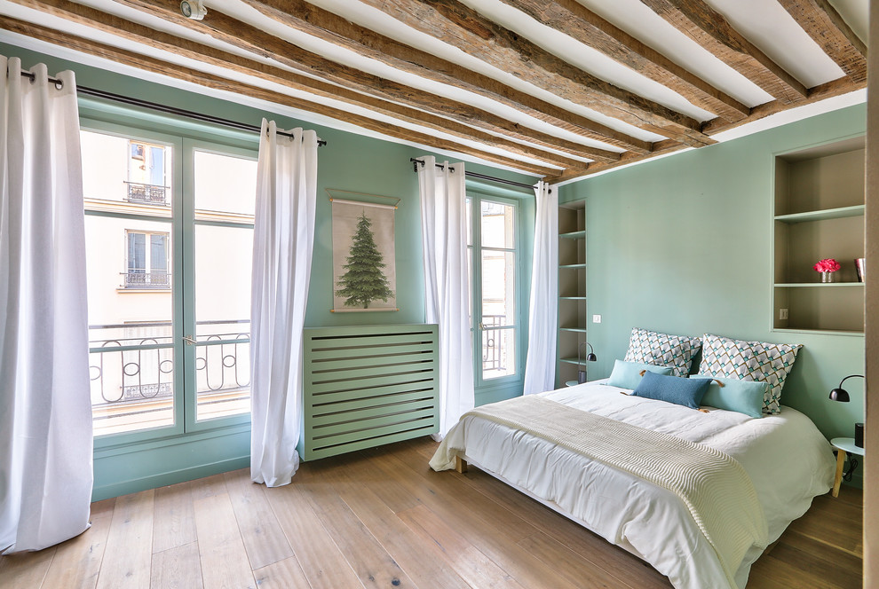 Large scandinavian guest bedroom in Paris with green walls, light hardwood floors and brown floor.