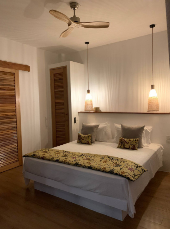 Idee per una camera matrimoniale tropicale di medie dimensioni con pareti beige, pavimento in laminato e pavimento beige
