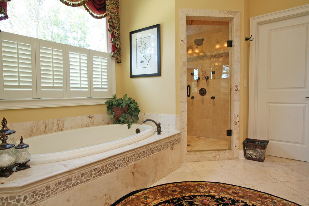 This is an example of a large traditional master bathroom in Atlanta with recessed-panel cabinets, dark wood cabinets, a drop-in tub, a corner shower, a two-piece toilet, beige tile, travertine, yellow walls, porcelain floors, an undermount sink, granite benchtops, an open shower and multi-coloured benchtops.