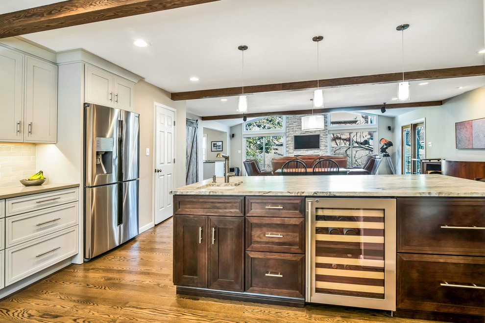 Transitional medium tone wood floor and brown floor eat-in kitchen photo in DC Metro with a farmhouse sink, shaker cabinets, white cabinets, granite countertops, white backsplash, subway tile backsplash, stainless steel appliances, an island and multicolored countertops