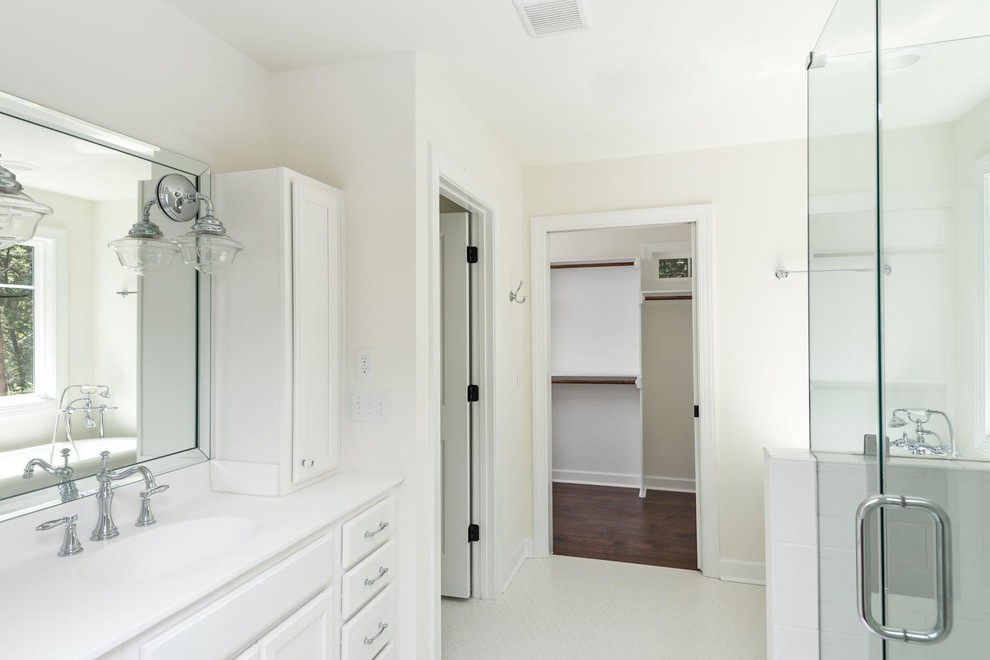 Photo of a medium sized classic ensuite bathroom in Raleigh with recessed-panel cabinets, white cabinets, a freestanding bath, an alcove shower, a two-piece toilet, white tiles, ceramic tiles, white walls, ceramic flooring, an integrated sink and granite worktops.