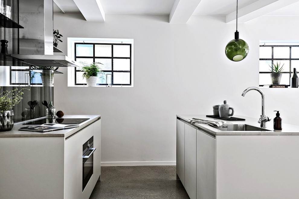 This is an example of a mid-sized scandinavian galley kitchen in Gothenburg with flat-panel cabinets, white cabinets, black splashback, stainless steel appliances, concrete floors and with island.
