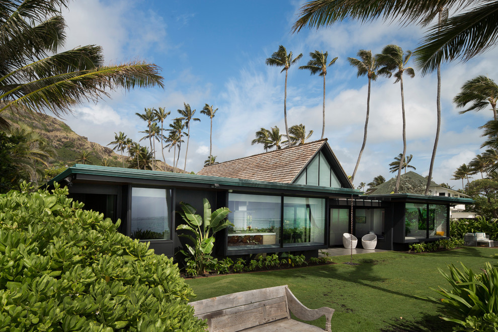 Contemporary one-storey black house exterior in Hawaii with a gable roof and a shingle roof.