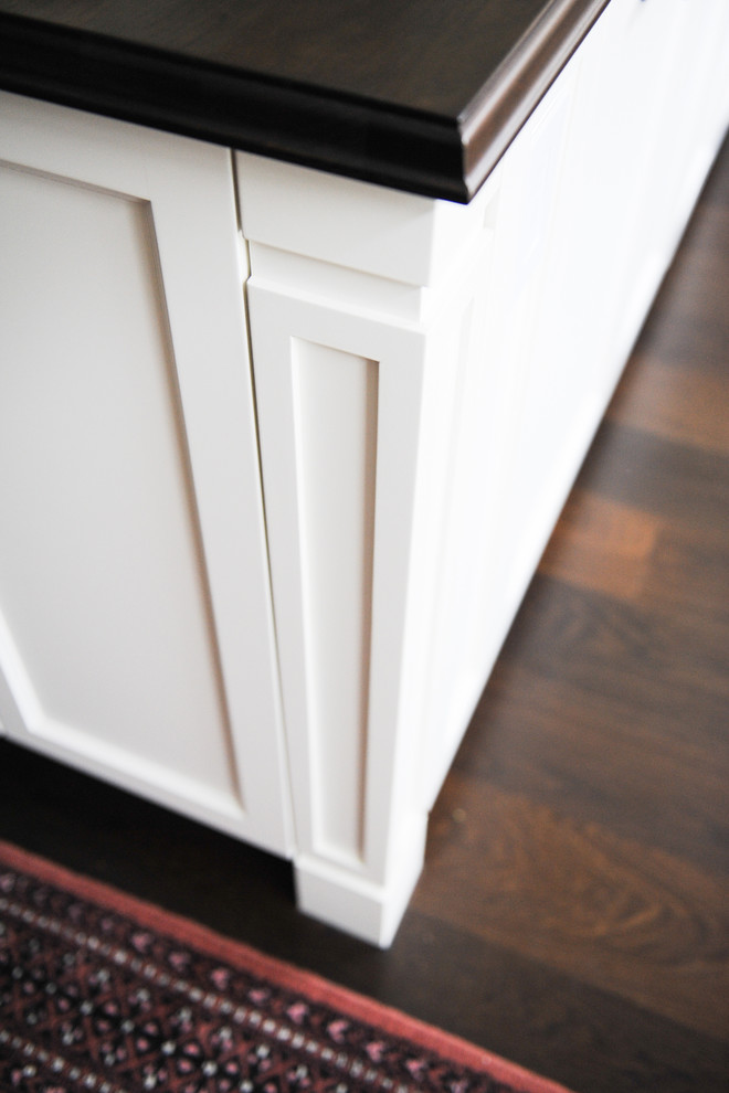 Inspiration for a mid-sized transitional u-shaped dark wood floor home design remodel in Vancouver with an undermount sink, recessed-panel cabinets, white cabinets, wood countertops, beige backsplash, terra-cotta backsplash, stainless steel appliances and an island