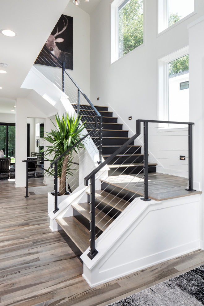 This is an example of a large contemporary wood u-shaped staircase in Minneapolis with painted wood risers and cable railing.