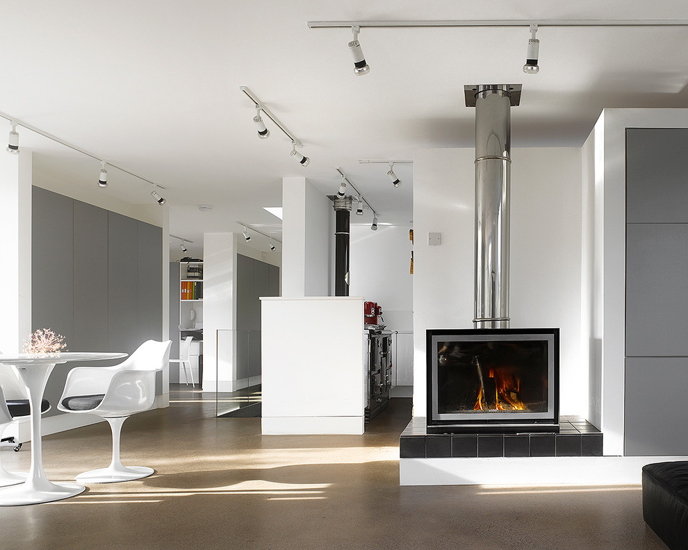 Inspiration for a large contemporary open concept living room in London with concrete floors and a wood stove.