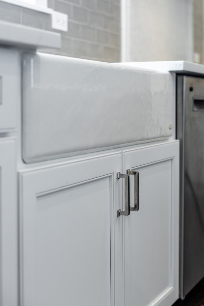 Inspiration for a large transitional u-shaped dark wood floor and brown floor eat-in kitchen remodel in Chicago with a farmhouse sink, beaded inset cabinets, white cabinets, quartz countertops, gray backsplash, glass tile backsplash, stainless steel appliances, an island and white countertops