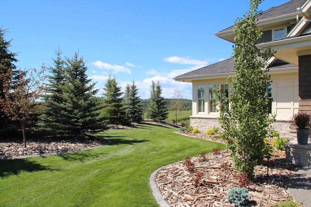 This is an example of a mid-sized transitional full sun front yard stone retaining wall landscape in Calgary.