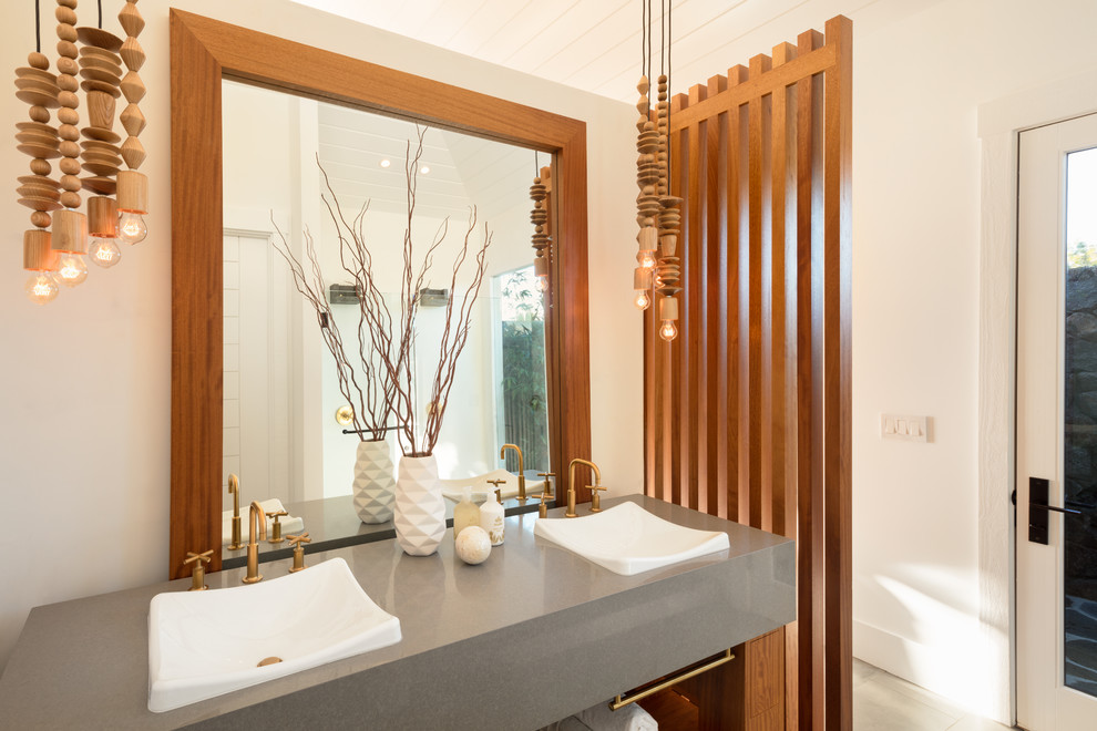 Large tropical master bathroom in Hawaii with open cabinets, a freestanding tub, a corner shower, a one-piece toilet, white tile, white walls, ceramic floors, a vessel sink, engineered quartz benchtops, grey floor, an open shower and medium wood cabinets.