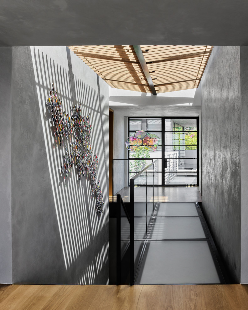 Idee per un grande corridoio design con pareti grigie e pavimento in legno massello medio
