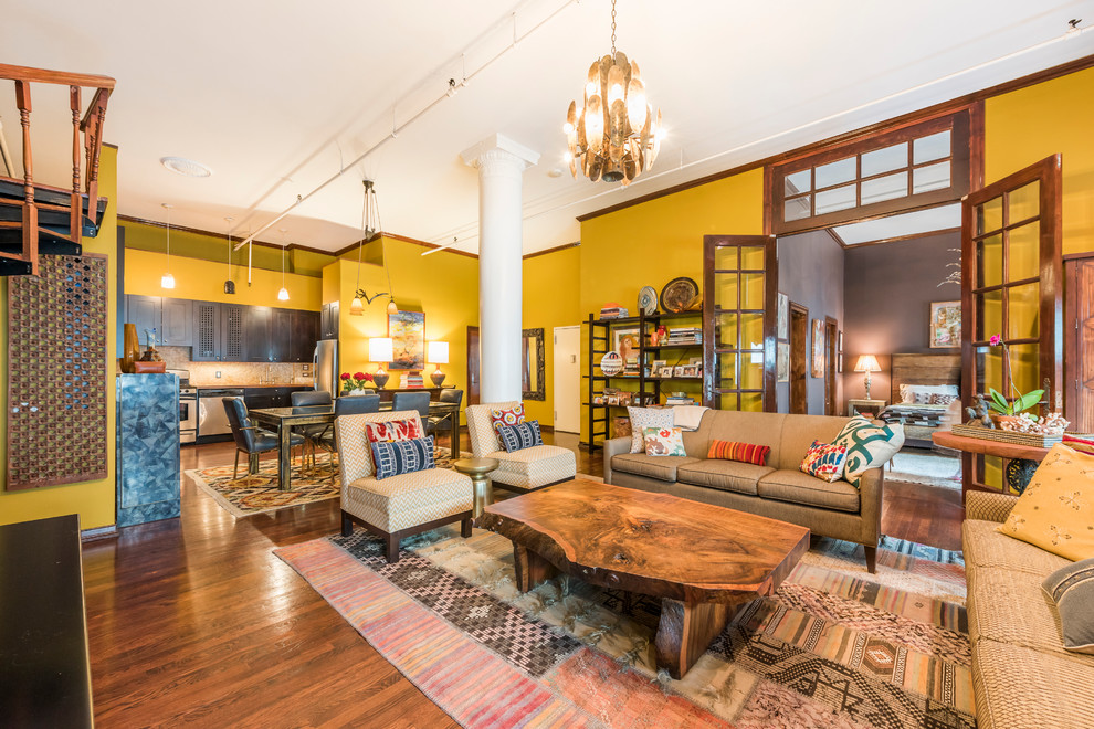 Expansive eclectic open concept living room in New York with yellow walls, dark hardwood floors and no fireplace.