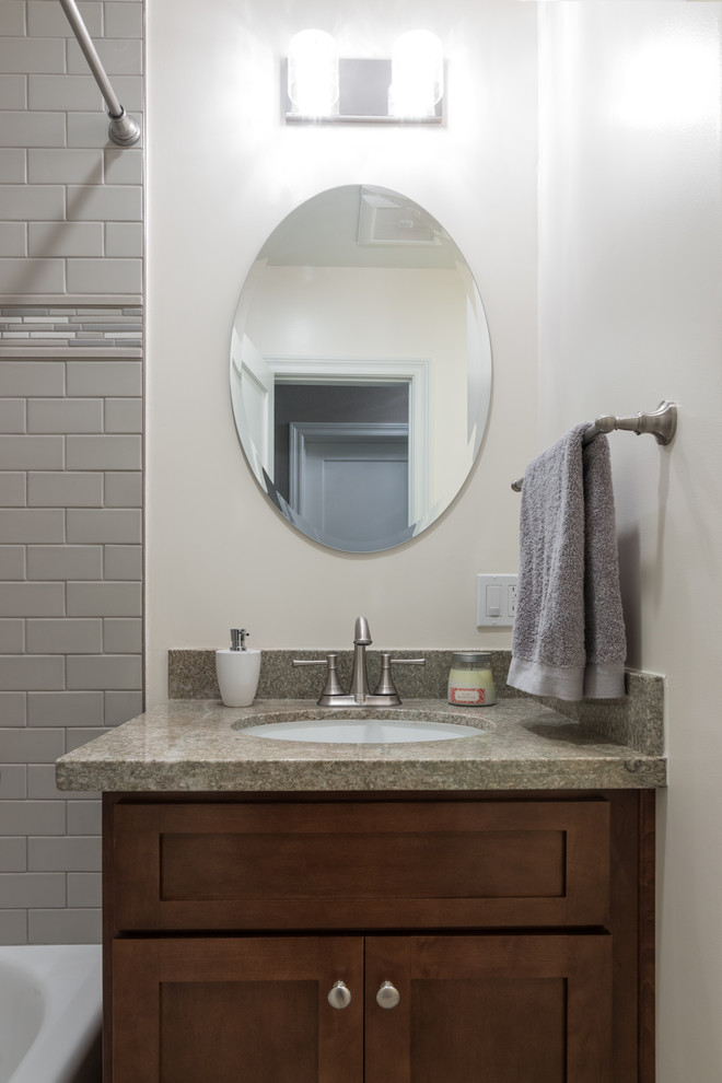 Photo of a mid-sized transitional bathroom in Los Angeles with shaker cabinets, medium wood cabinets, an alcove tub, a shower/bathtub combo, a two-piece toilet, green tile, ceramic tile, green walls, porcelain floors, an undermount sink, granite benchtops, grey floor and a shower curtain.