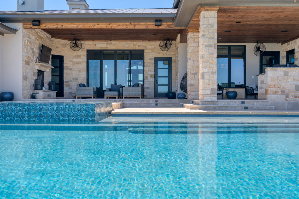 Cette image montre une grande piscine arrière minimaliste rectangle avec un bain bouillonnant et des pavés en pierre naturelle.