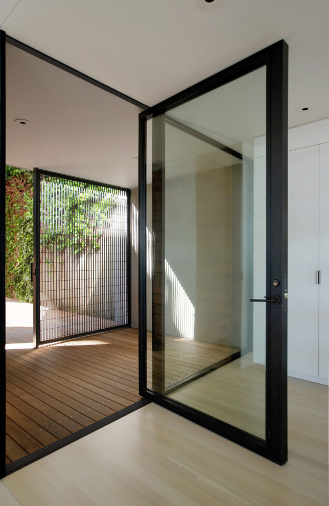 На фото: входная дверь в стиле модернизм с белыми стенами, темным паркетным полом, поворотной входной дверью, стеклянной входной дверью и бежевым полом