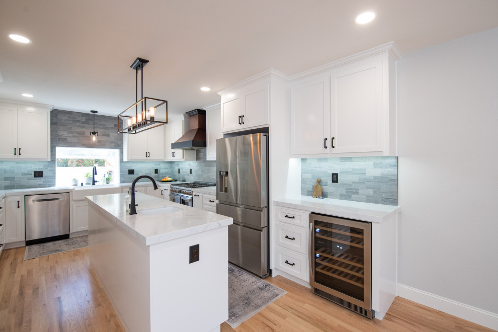 Design ideas for a modern eat-in kitchen in Sacramento with a farmhouse sink, shaker cabinets, white cabinets, quartz benchtops, grey splashback, ceramic splashback, stainless steel appliances, with island and white benchtop.