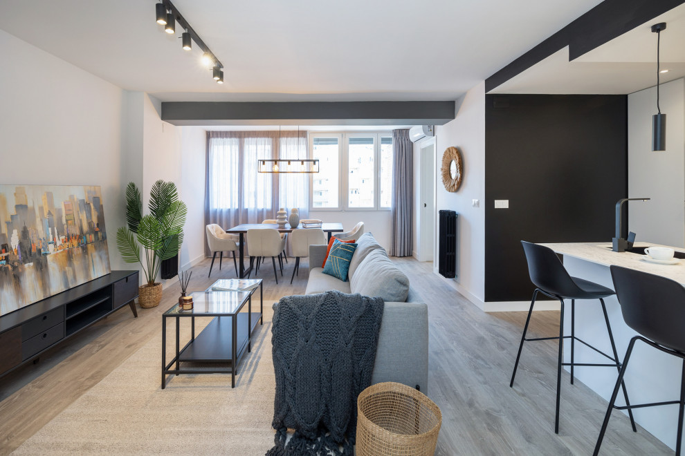 Immagine di una grande sala da pranzo aperta verso il soggiorno minimalista con pareti bianche, pavimento in laminato e pavimento beige