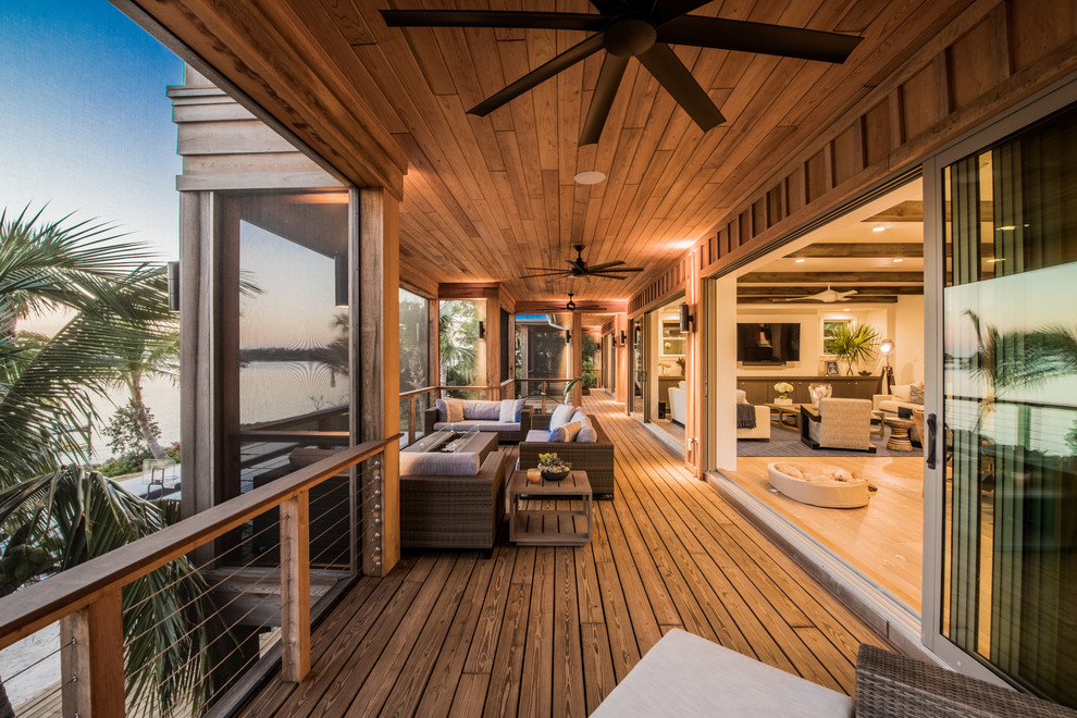 This is an example of a tropical deck in Tampa with a fire feature and a roof extension.