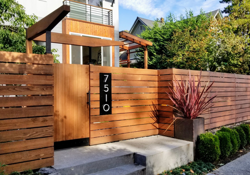 Contemporary front yard full sun garden in Seattle with a garden path, concrete pavers and a wood fence for fall.