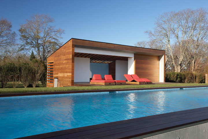 This is an example of a large modern backyard rectangular lap pool in New York with a pool house and decking.