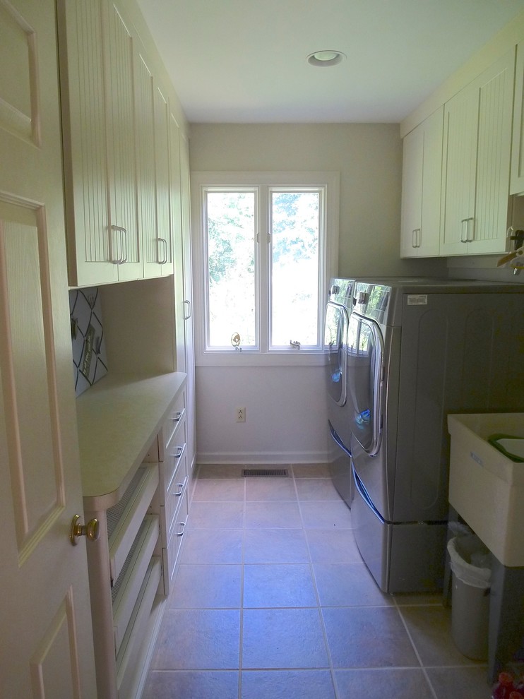 Photo of a mid-sized traditional galley laundry room in Other with an utility sink, beaded inset cabinets, beige cabinets, laminate benchtops and a side-by-side washer and dryer.