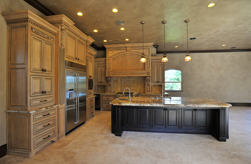 This is an example of a large mediterranean l-shaped kitchen in Sacramento with a double-bowl sink, raised-panel cabinets, beige cabinets, marble benchtops, beige splashback, stone tile splashback, stainless steel appliances and travertine floors.