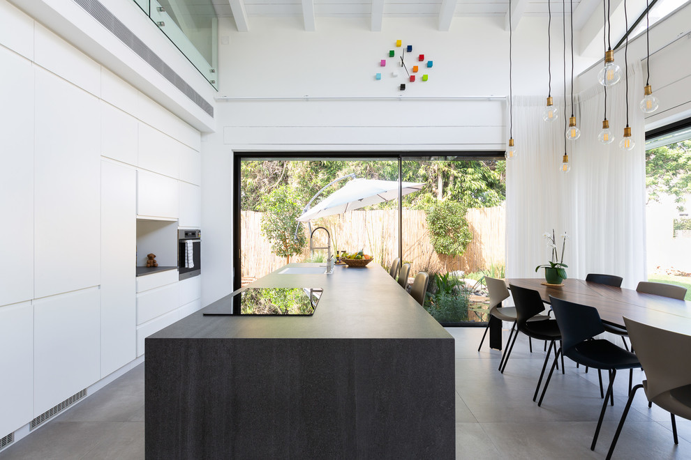 Design ideas for a midcentury eat-in kitchen in Tel Aviv with a single-bowl sink, flat-panel cabinets, white cabinets, stainless steel appliances, concrete floors, with island, grey floor and brown benchtop.