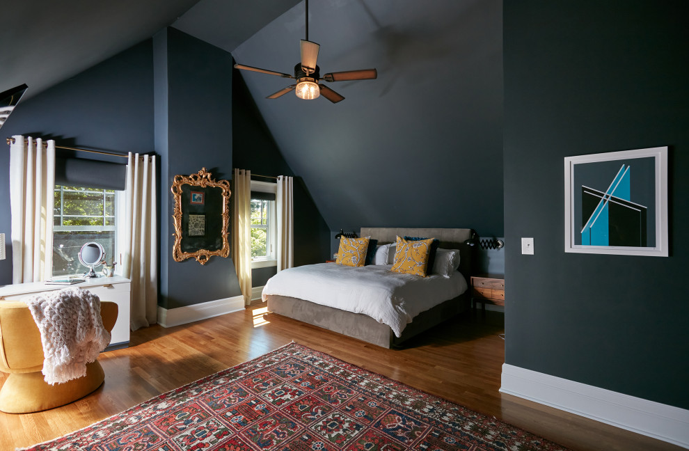 Photo of a large master bedroom in New York with blue walls, medium hardwood floors, brown floor and vaulted.