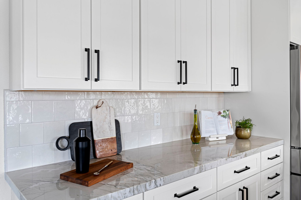 Transitional vinyl floor and brown floor kitchen photo with a farmhouse sink, shaker cabinets, white cabinets, quartzite countertops, white backsplash and stainless steel appliances