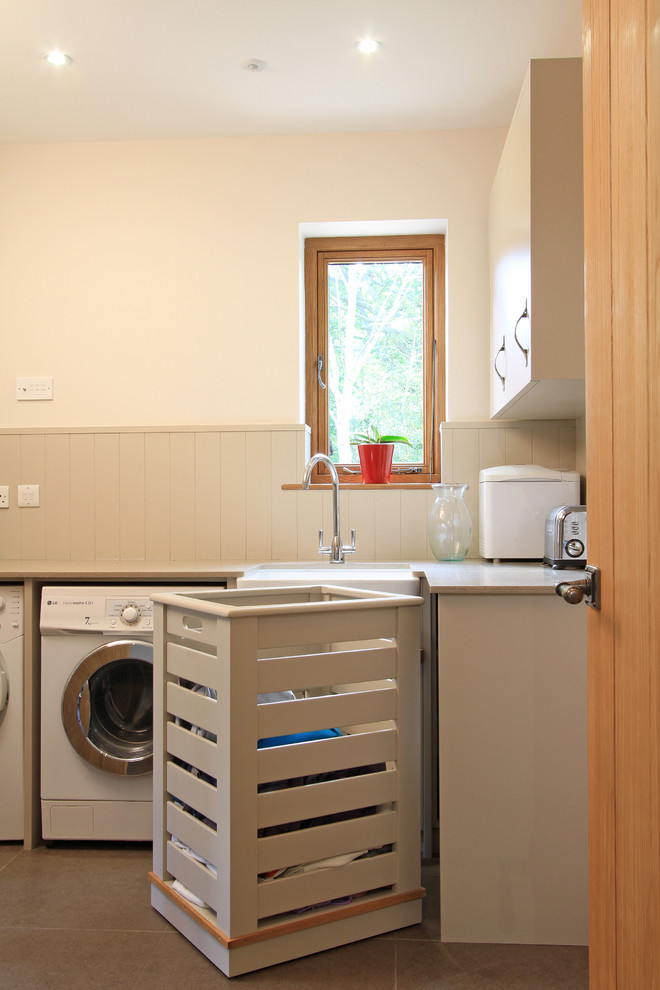 Design ideas for a large contemporary l-shaped utility room in Hampshire with an undermount sink, flat-panel cabinets, beige cabinets, quartz benchtops, white walls, porcelain floors and a side-by-side washer and dryer.