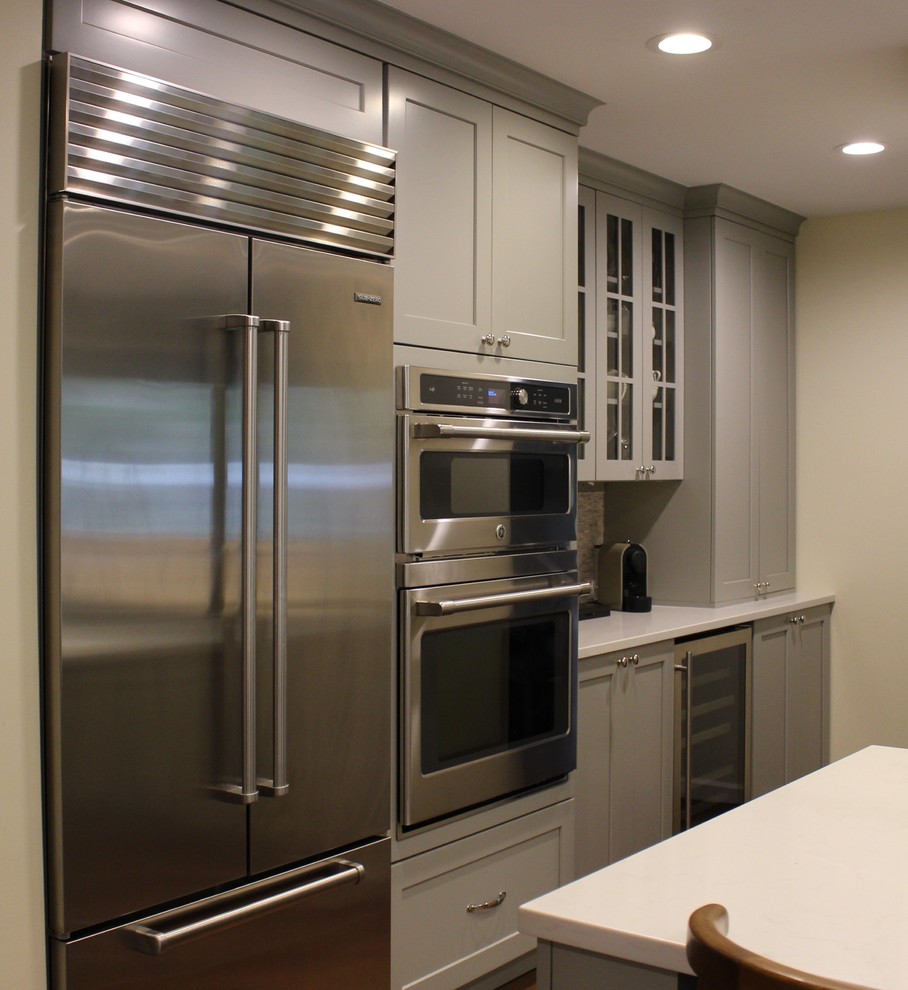 Inspiration for a mid-sized transitional u-shaped dark wood floor eat-in kitchen remodel in Seattle with a farmhouse sink, shaker cabinets, gray cabinets, quartzite countertops, gray backsplash, stone tile backsplash, stainless steel appliances and an island